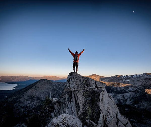 A climber reaches the summit of an exposed mountain top in the Tahoe backcountry, California