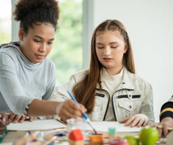 Group of diversity students enjoy drawing and painting in arts class with friends. happy smiling kids using paintbrush sketching on paper. support creative skill in a classroom at school.